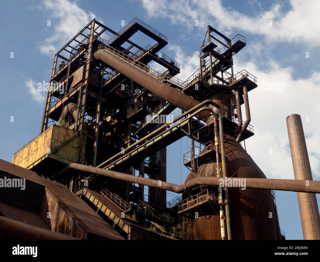 Vecchie tubature e edifici arrugginiti nella regione di Ostrava Vitkovice al tramonto Foto Stock
