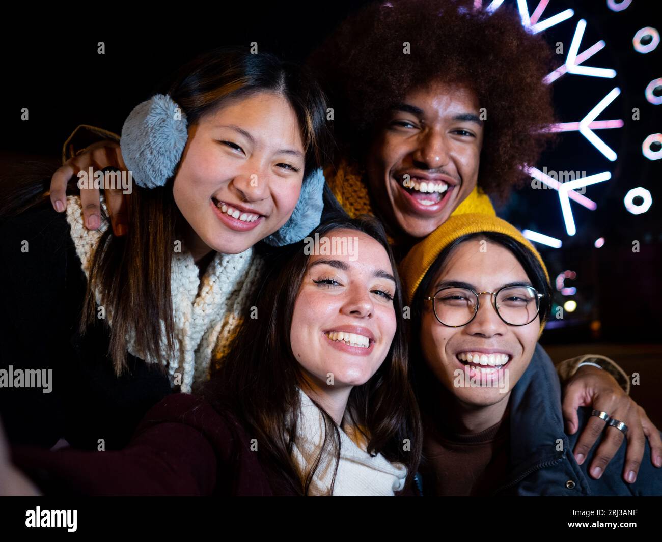 Un gruppo di diversi amici in abiti invernali guarda la fotocamera sorridente e divertiti in città Foto Stock