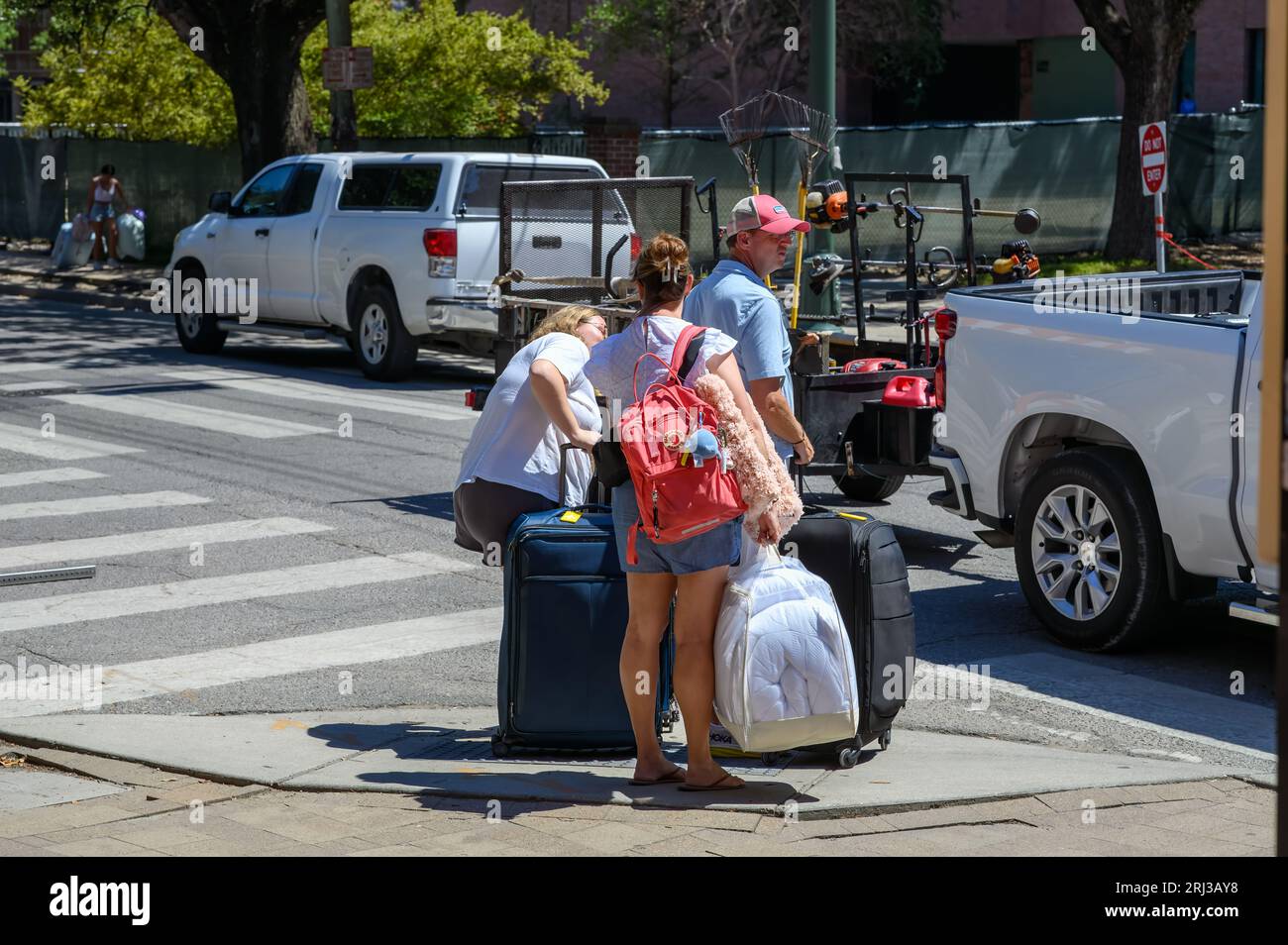 NEW ORLEANS, LOUISIANA, USA - 17 AGOSTO 2023: Madre, padre e figlia aspettano all'incrocio con i bagagli mentre spostano la figlia nel dormitorio Foto Stock
