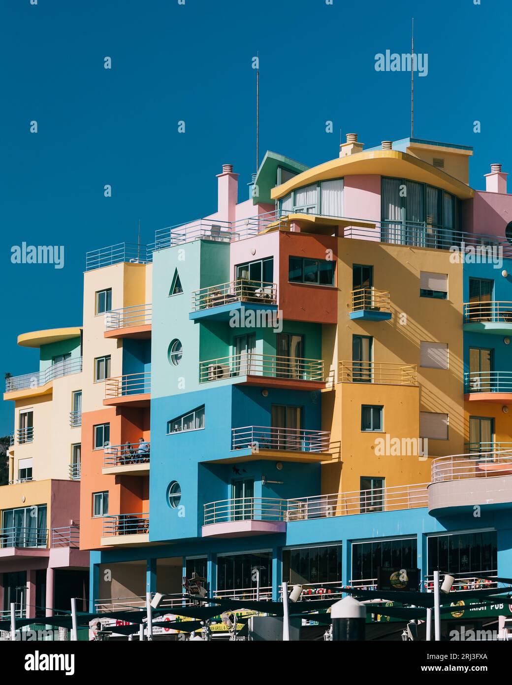 Un edificio dai colori vivaci adagiato sullo sfondo di una barca e di più piccole imbarcazioni in un corpo d'acqua Foto Stock