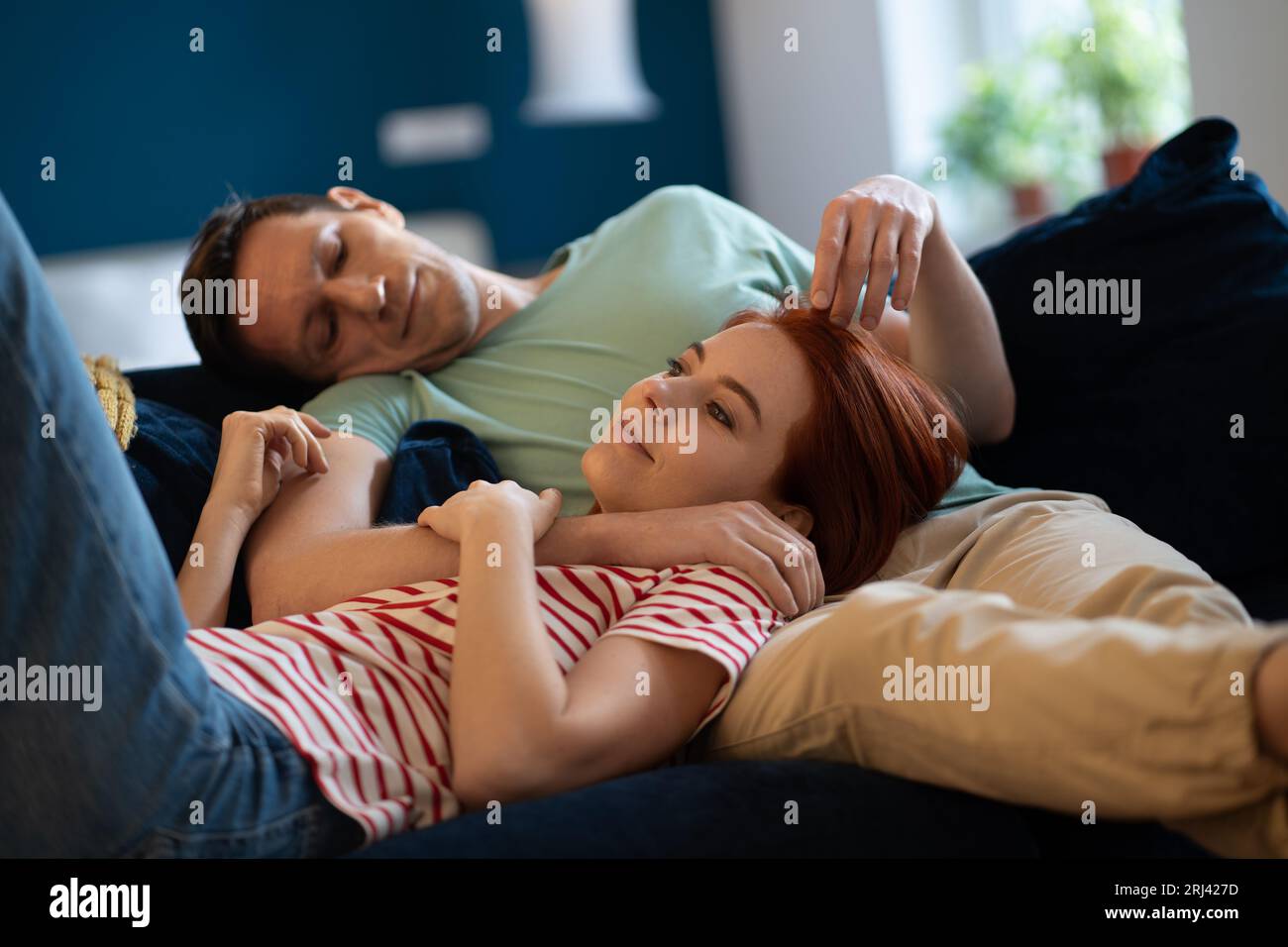 Adorabile coppia di famiglie che si rilassano sul divano a casa. Moglie e marito riposati che sognano insieme Foto Stock