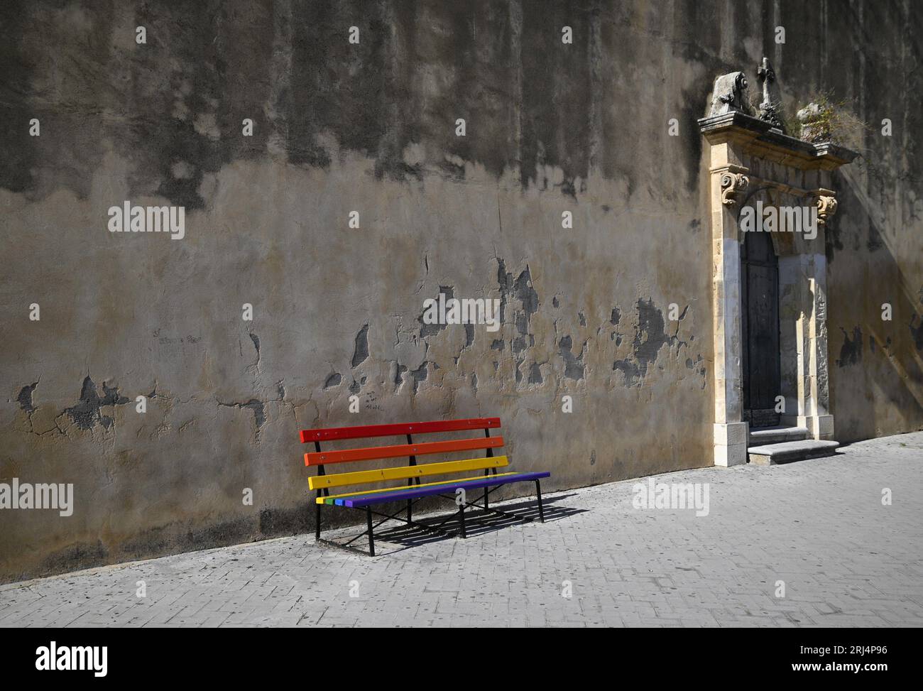 Panchina colorata in legno contro le pareti in stucco di stile barocco siciliano Chiesa della Madonna del Carmine in via Aleardi a Scicli Foto Stock