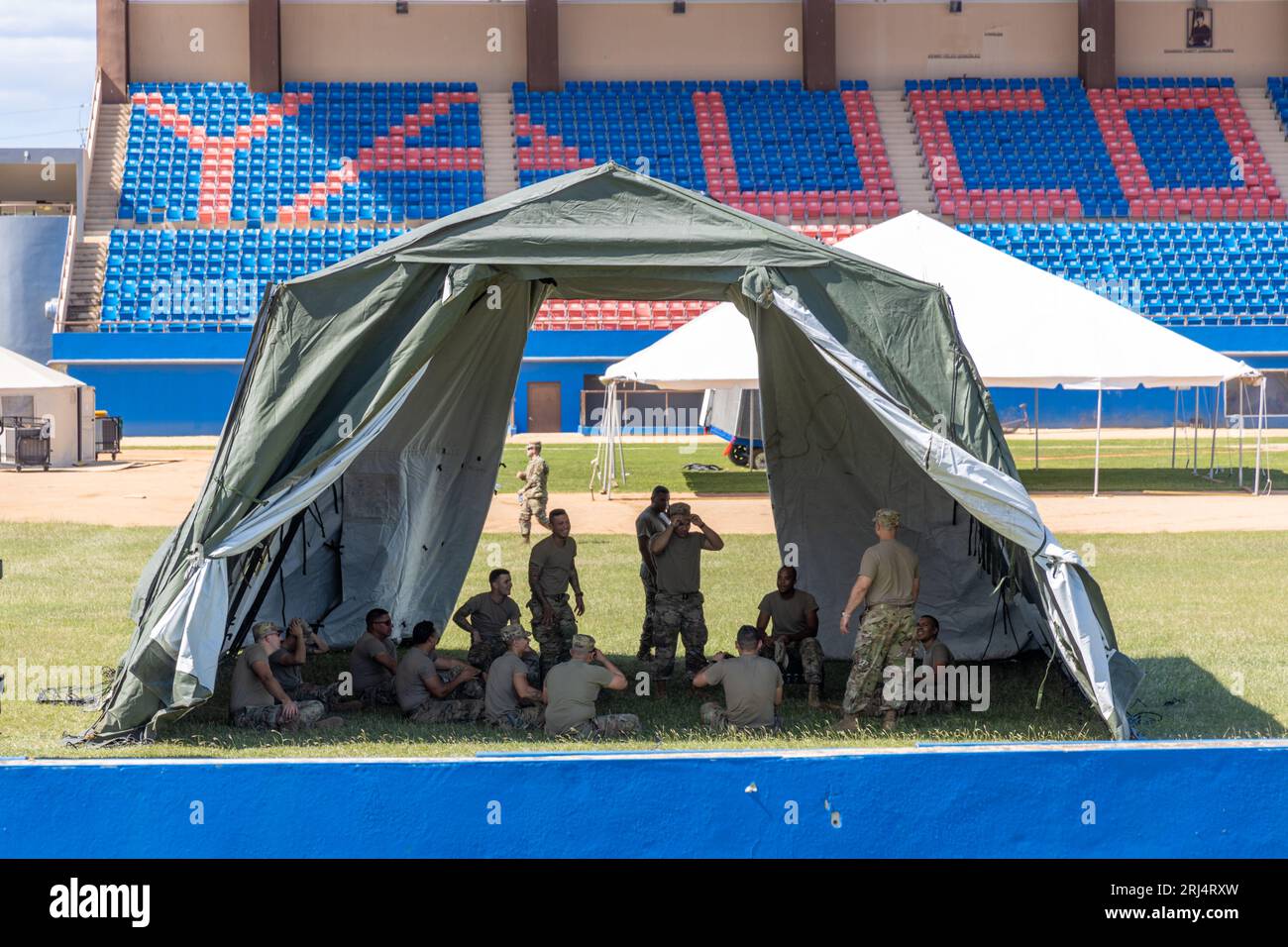 Un gruppo di militari è riunito all'interno di una spaziosa tenda in un grande stadio Foto Stock