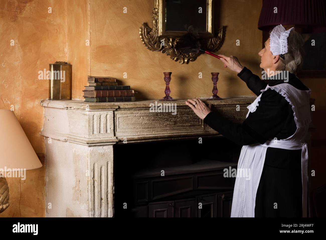 Cameriera vittoriana o cameriera in abito nero, berretto in pizzo e grembiule bianco che lavorano in un interno del XIX secolo Foto Stock