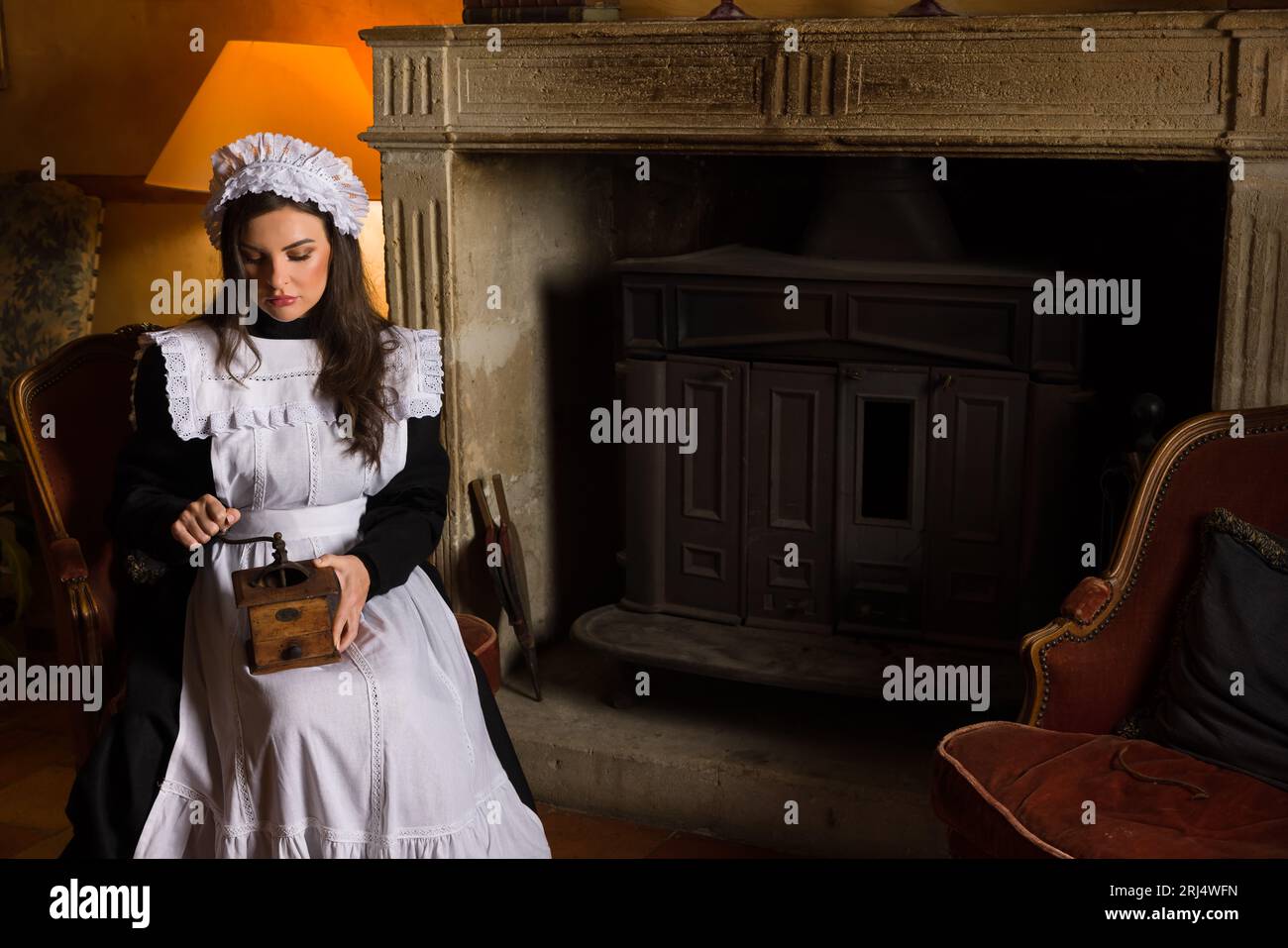 Scene di una bellissima giovane cameriera vittoriana che fa le faccende di casa in un interno antico Foto Stock