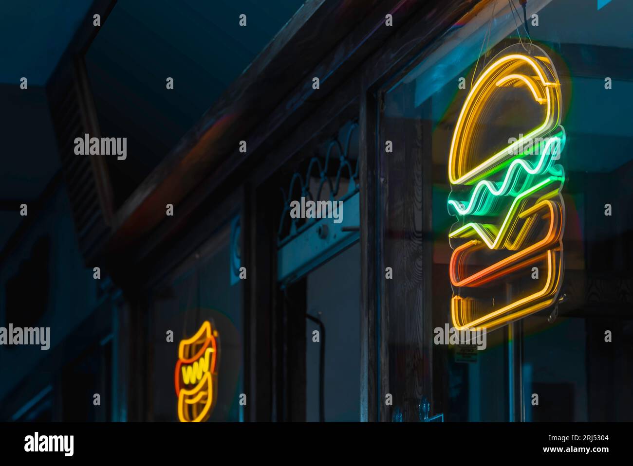 Fast food aperto di sera con un cartello al neon per hamburger Foto Stock