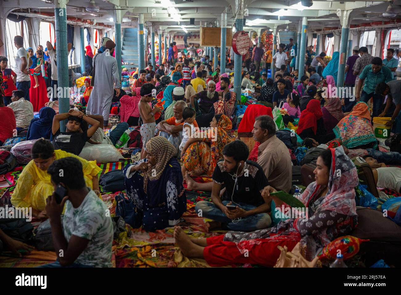 Le persone viaggiano su un ponte all'interno di un traghetto mentre tornano ai loro villaggi per celebrare il festival Eid-al-Adha, al terminal di lancio di Sadarghat a Dacca, Foto Stock