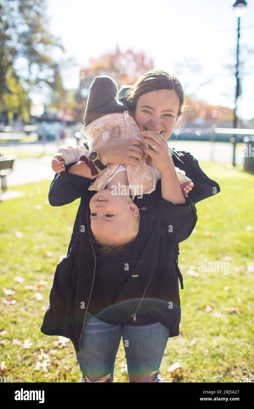 Una giovane madre tiene la sua bambina al contrario. Foto Stock