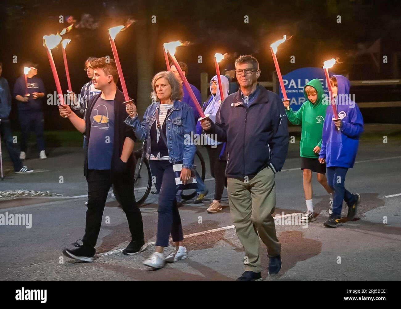 Bridport, Dorset, Regno Unito. 20 agosto 2023. Centinaia di residenti e visitatori, giovani e anziani, che tenevano torce fiammeggianti, hanno partecipato all'annuale processione delle fiaccole del Carnevale di Bridport nel Dorset. La processione guidata dal sindaco della città Dave Bolwell e dal cittadino crier John Collingwood, partì dal municipio di Bridport a South Street e terminò a East Beach a West Bay a tre chilometri di distanza, dove la serata si concluse con un falò, musica e fuochi d'artificio per chiudere i festeggiamenti del fine settimana di carnevale. Foto: Graham Hunt/Alamy Live News Foto Stock