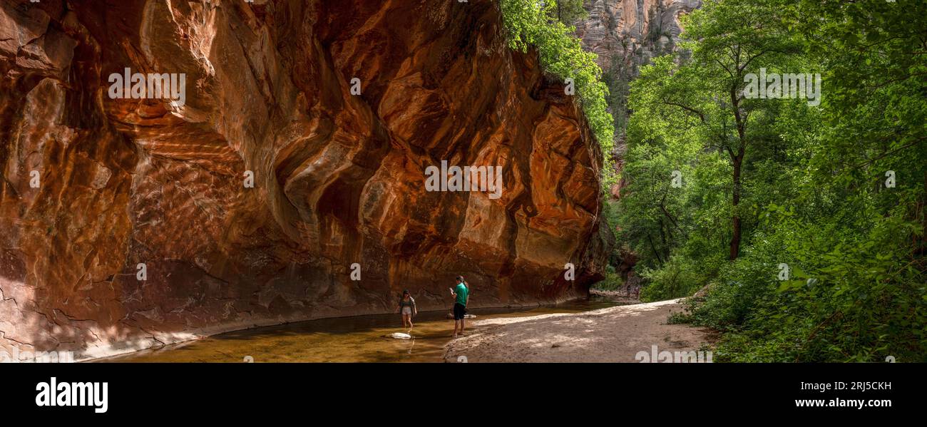 Le giovani coppie si godono il sole in un ruscello sotto la roccia Foto Stock