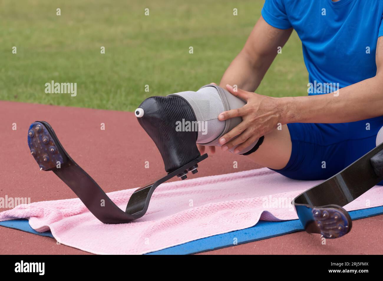 Atleta paralimpico asiatico dotato di lame da corsa protesiche in uno stadio sportivo. Foto Stock