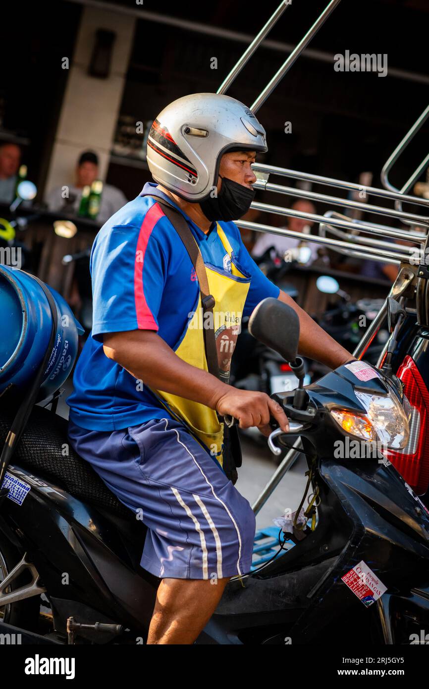 Un uomo tailandese corre lungo Soi Buakhao, Pattaya, Thailandia sulla sua moto. Foto Stock