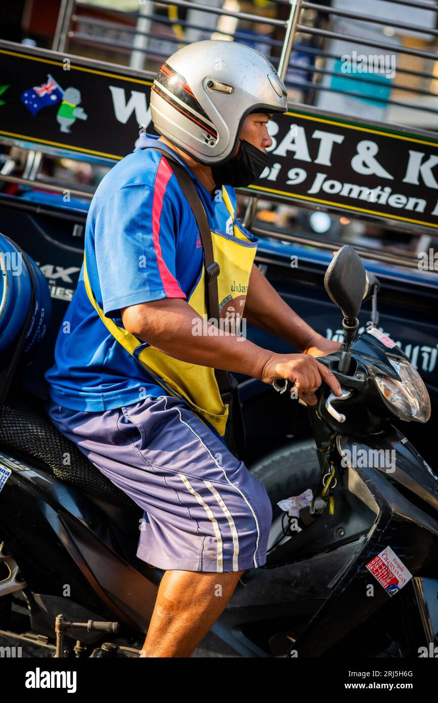 Un uomo tailandese corre lungo Soi Buakhao, Pattaya, Thailandia sulla sua moto. Foto Stock