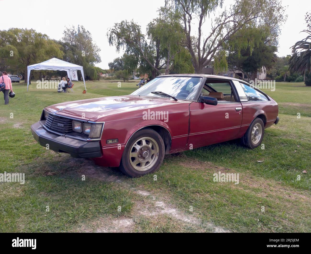 Vecchio coupé rosso Bordeaux Toyota Celica serie B circa 1980 sul prato. Natura, erba, alberi. Mostra di auto d'epoca CAACMACH 2023. Foto Stock