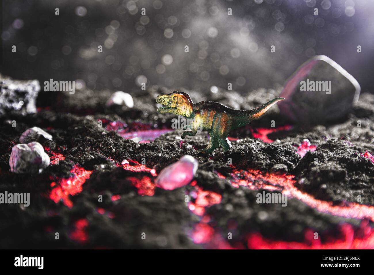 Tyrannosaurus su una pietra fugge dalla lava bruciata. Un paesaggio creativo e incandescente con una piccola miniatura. Fine dell'era dei dinosauri. Foto Stock