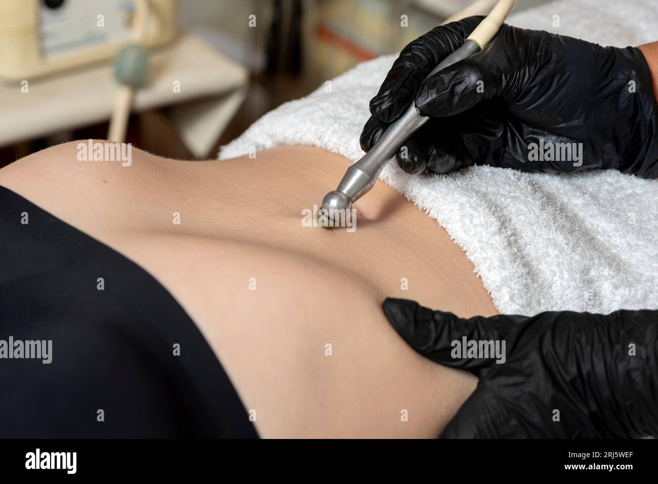 Una paziente che riceve un trattamento estetico del corpo non invasivo con un metodo a punta diamantata per migliorare l'aspetto della pelle e dell'addome Foto Stock