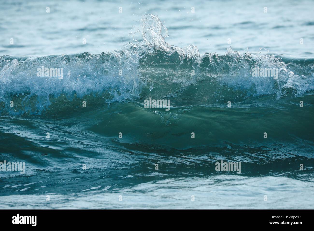 Una foto panoramica di un oceano tranquillo con un'ampia gamma di onde che si infrangono sulla costa Foto Stock