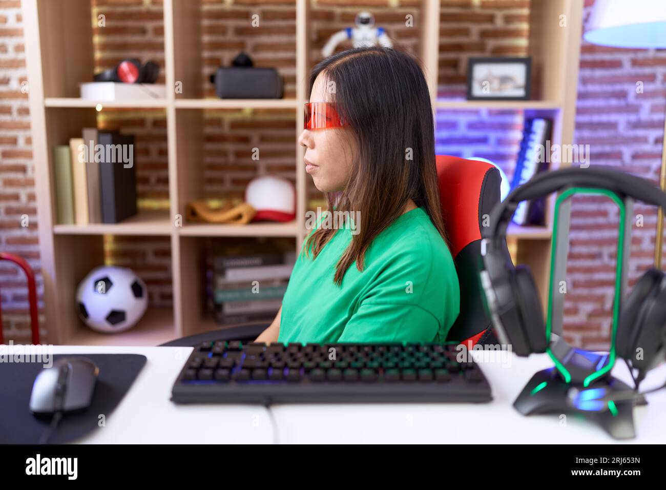 Donna cinese di mezza età che indossa occhiali per realtà virtuale che guardano di lato, rilassa la posa del profilo con il viso naturale e sorriso sicuro. Foto Stock