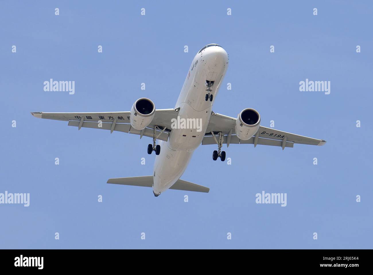 Un aereo cinese orientale con il suo carrello di atterraggio si estendeva in volo attraverso il cielo Foto Stock