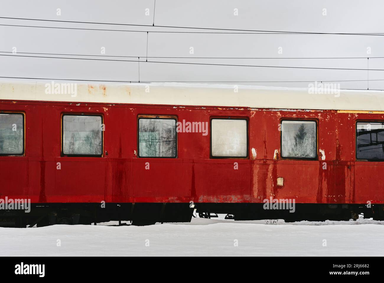 In un paesaggio innevato si vede un treno passeggeri rosso vecchio, con una linea telefonica sullo sfondo Foto Stock