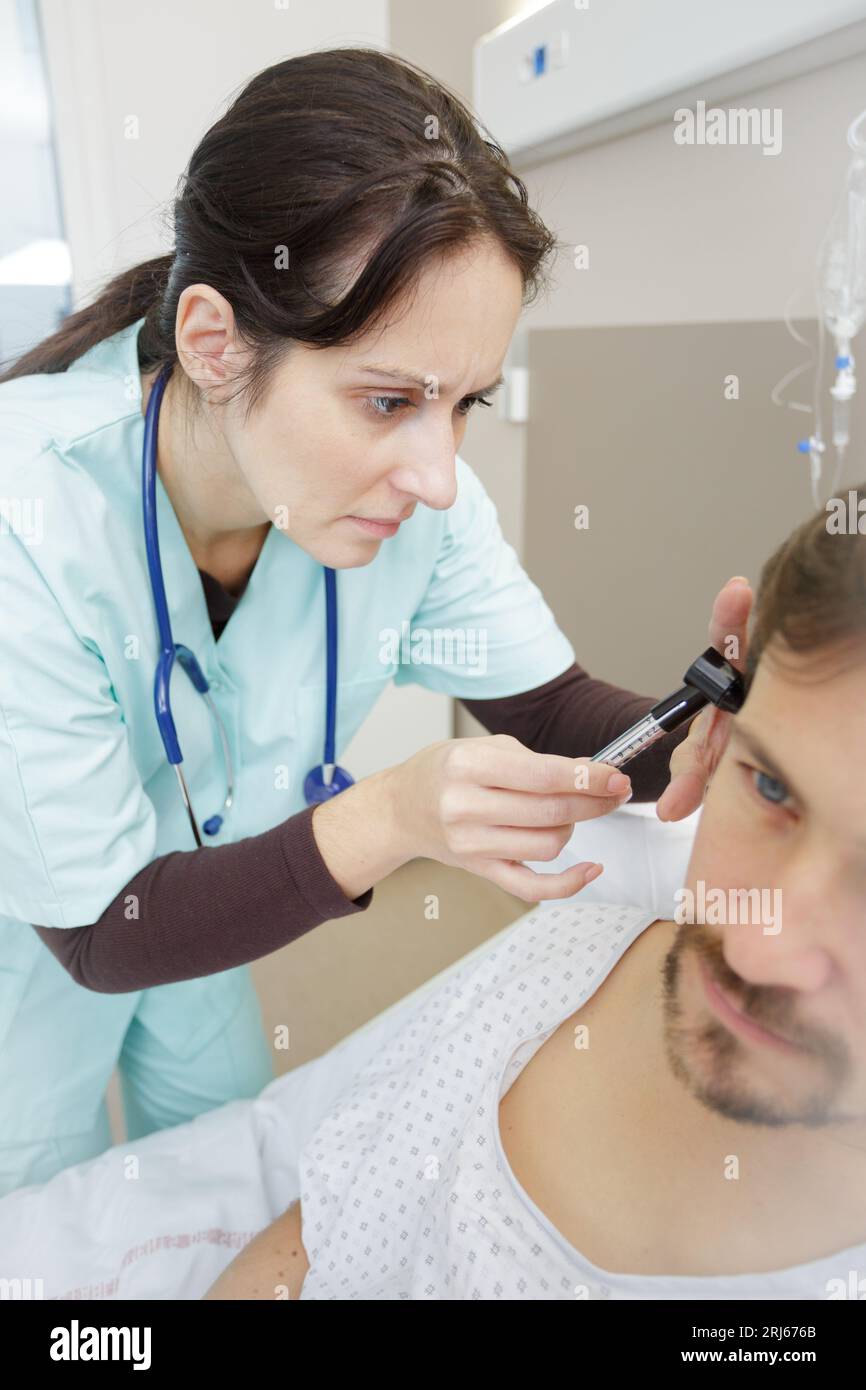 medico che inserisce l'apparecchio acustico nell'orecchio di mans Foto Stock