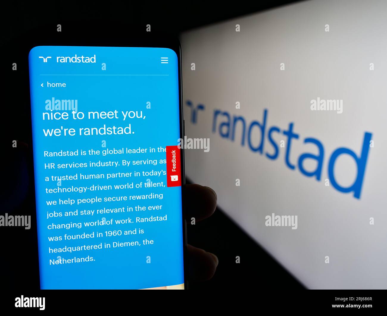 Persona in possesso di cellulare con pagina web dell'azienda olandese di risorse umane Randstad N.V. sullo schermo con logo. Concentrarsi sul centro del display del telefono. Foto Stock