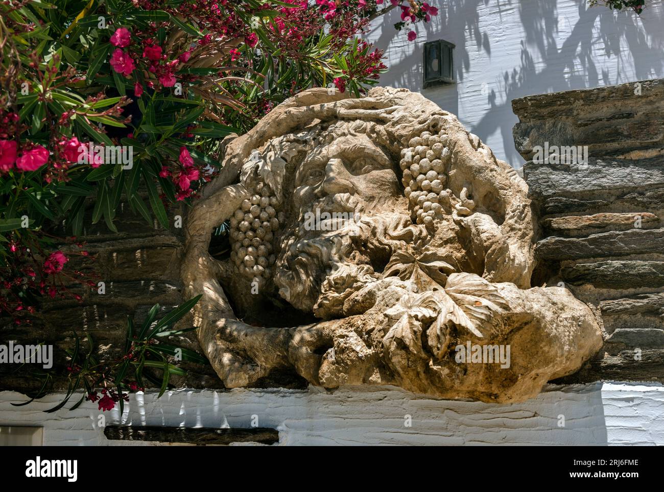 Testa scolpita di Dioniso, Dio del vino, nel villaggio di Komi, Tinos. Foto Stock