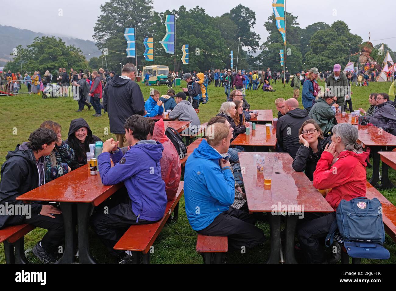 Persone sedute sotto la pioggia al festival Green Man, 2023 Foto Stock
