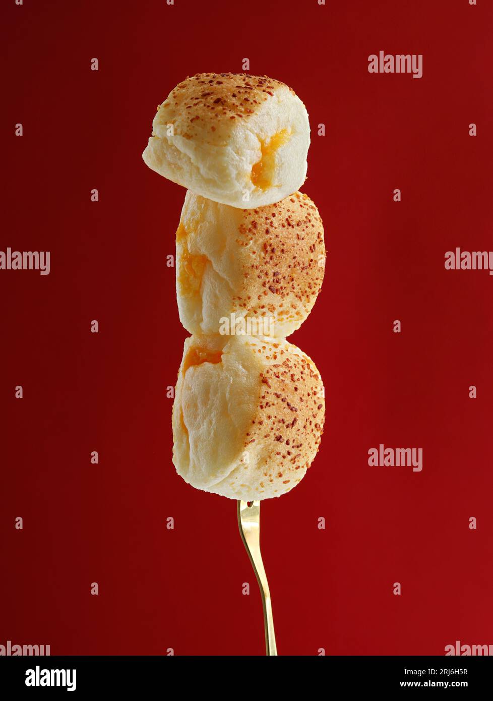Un primo piano di una forchetta con panini freschi su uno sfondo rosso brillante Foto Stock