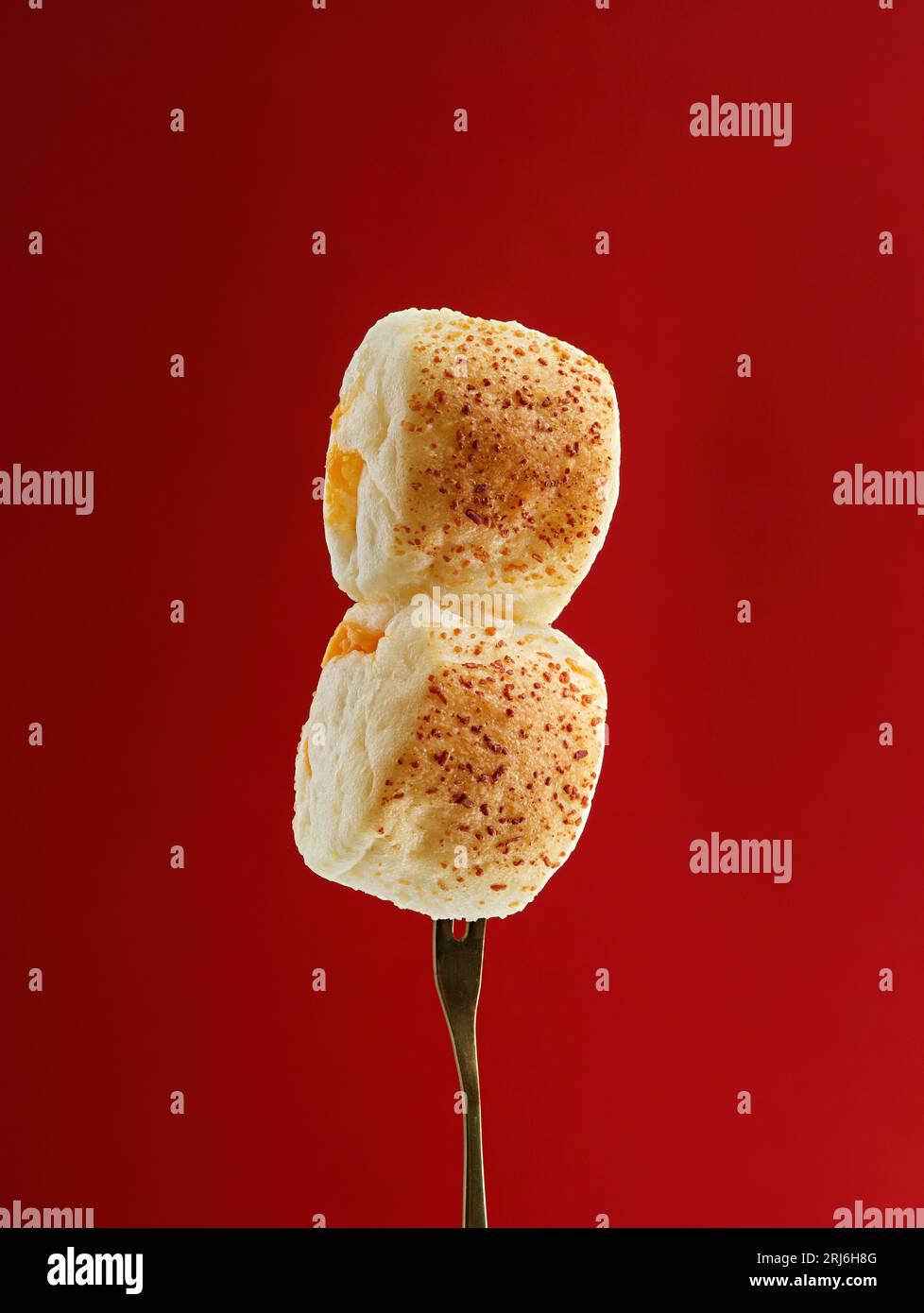 Un primo piano di una forchetta con panini freschi su uno sfondo rosso brillante Foto Stock
