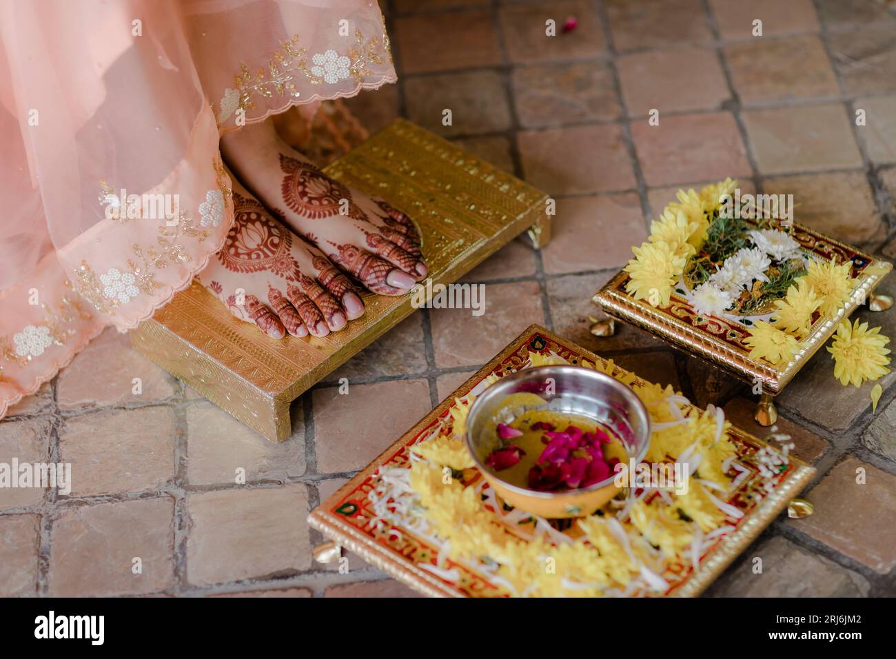 Un primo piano dei piedi di una sposa indiana con l'henné in cima a una superficie dorata Foto Stock Un primo piano dei piedi di una sposa indiana con l'henné in cima a una superficie dorata Foto Stock