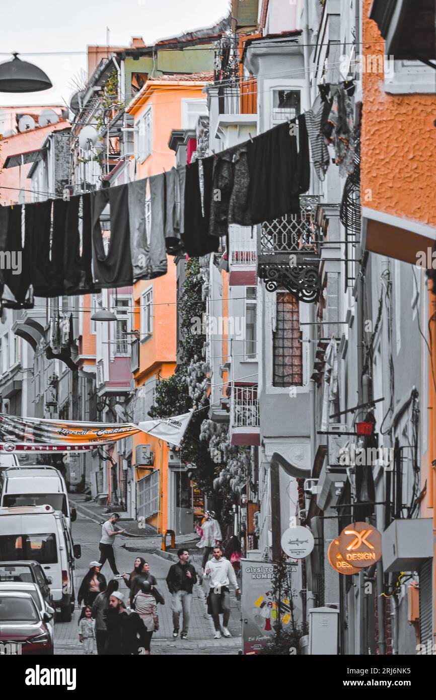 Questa foto mostra un gruppo di persone che camminano in città, lungo una stretta collina fiancheggiata da edifici alti Foto Stock