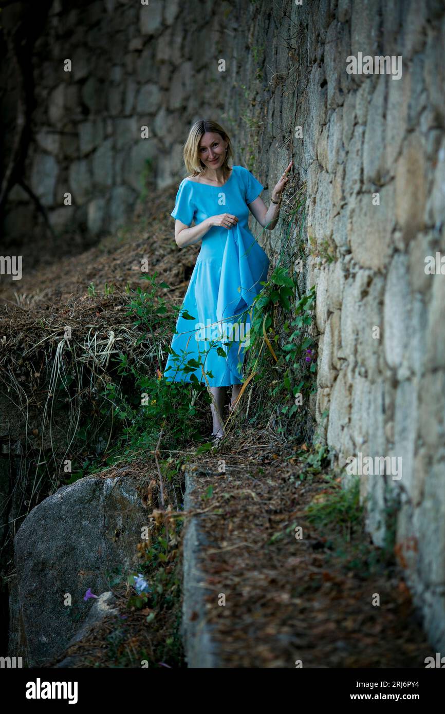 Una donna con un vestito blu vaga tra le rovine medievali. Foto Stock