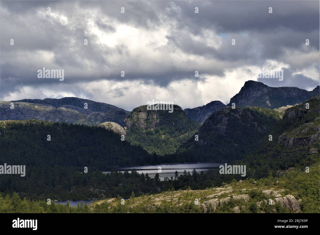 Immersa nella tranquilla escursione di Stavanger: Un tranquillo lago di montagna incorniciato da alberi e cime monumentali in pietra. La grandezza della natura in Norvegia. #MountainHike Foto Stock