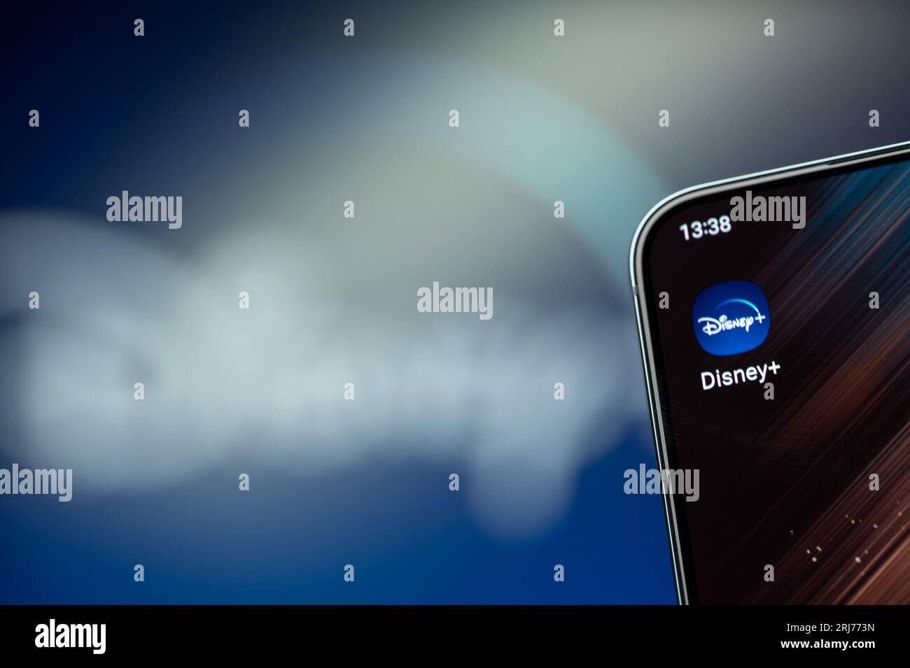 New York, USA - 21 agosto 2023: Uso dell'app Disney Plus sullo schermo dello smartphone in primo piano con sfondo sfocato del logo Foto Stock