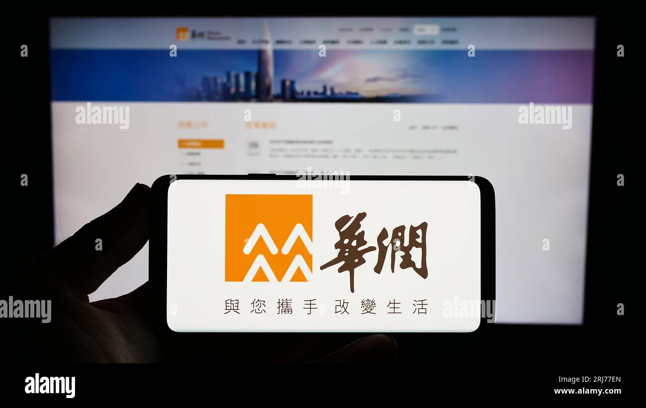 Persona che possiede uno smartphone con il logo di China Resources Holdings Company Limited (CRC) sullo schermo davanti al sito Web. Concentrarsi sul display del telefono. Foto Stock