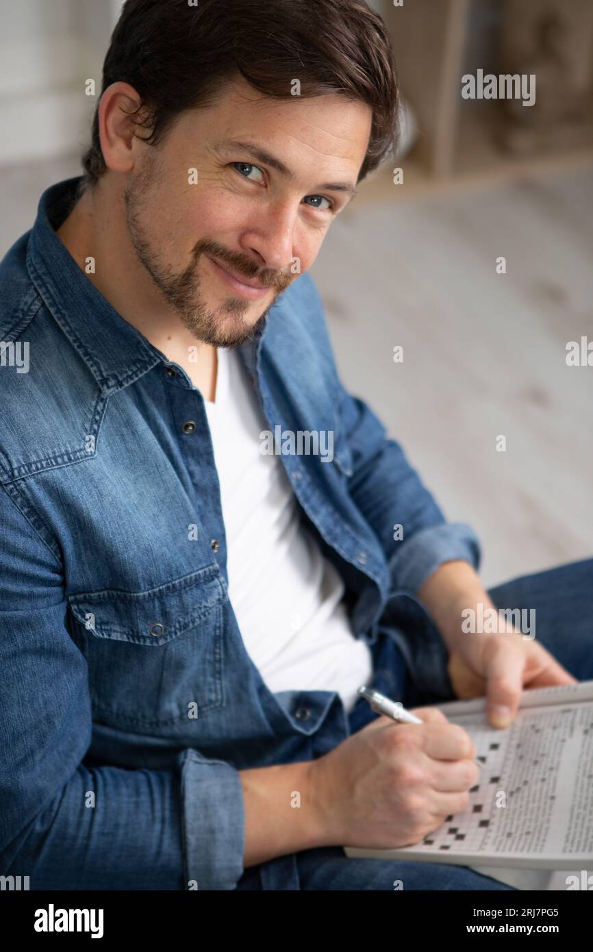 giovane uomo seduto facendo un puzzle crossword Foto Stock