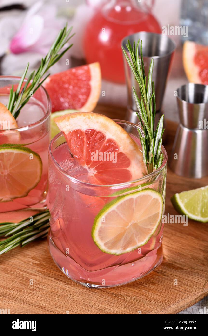 Cocktail biologico rinfrescante con fetta di pompelmo, lime e ramoscello di rosmarino in un bicchiere Foto Stock