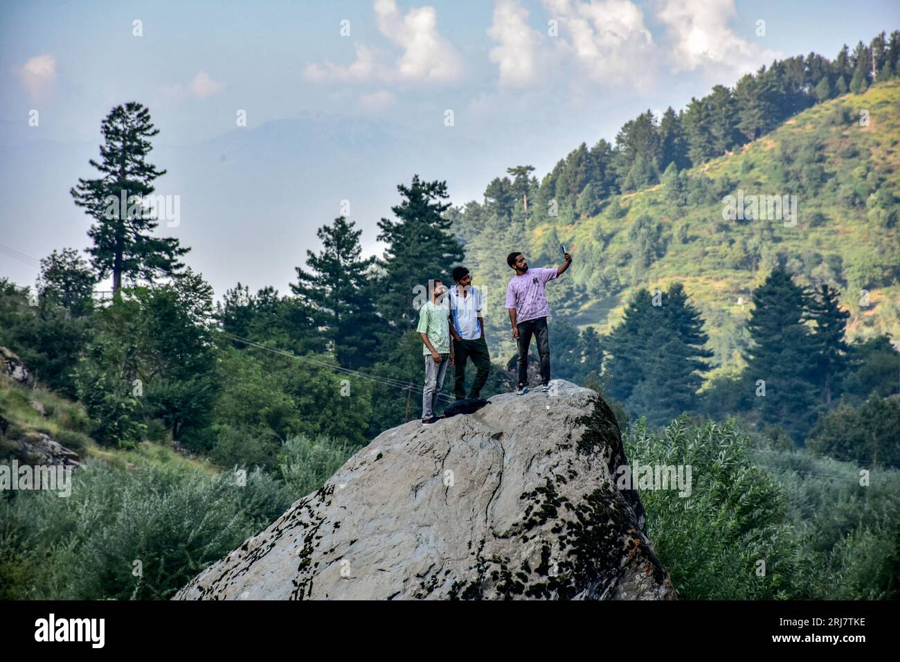 Ubriaco, India. 21 agosto 2023. Gli uomini del Kashmir si trovano sulla roccia mentre fanno un selfie durante una giornata calda e soleggiata a Drung, a circa 40 km da Srinagar, la capitale estiva del Jammu e del Kashmir. (Foto di Saqib Majeed/SOPA Images/Sipa USA) credito: SIPA USA/Alamy Live News Foto Stock