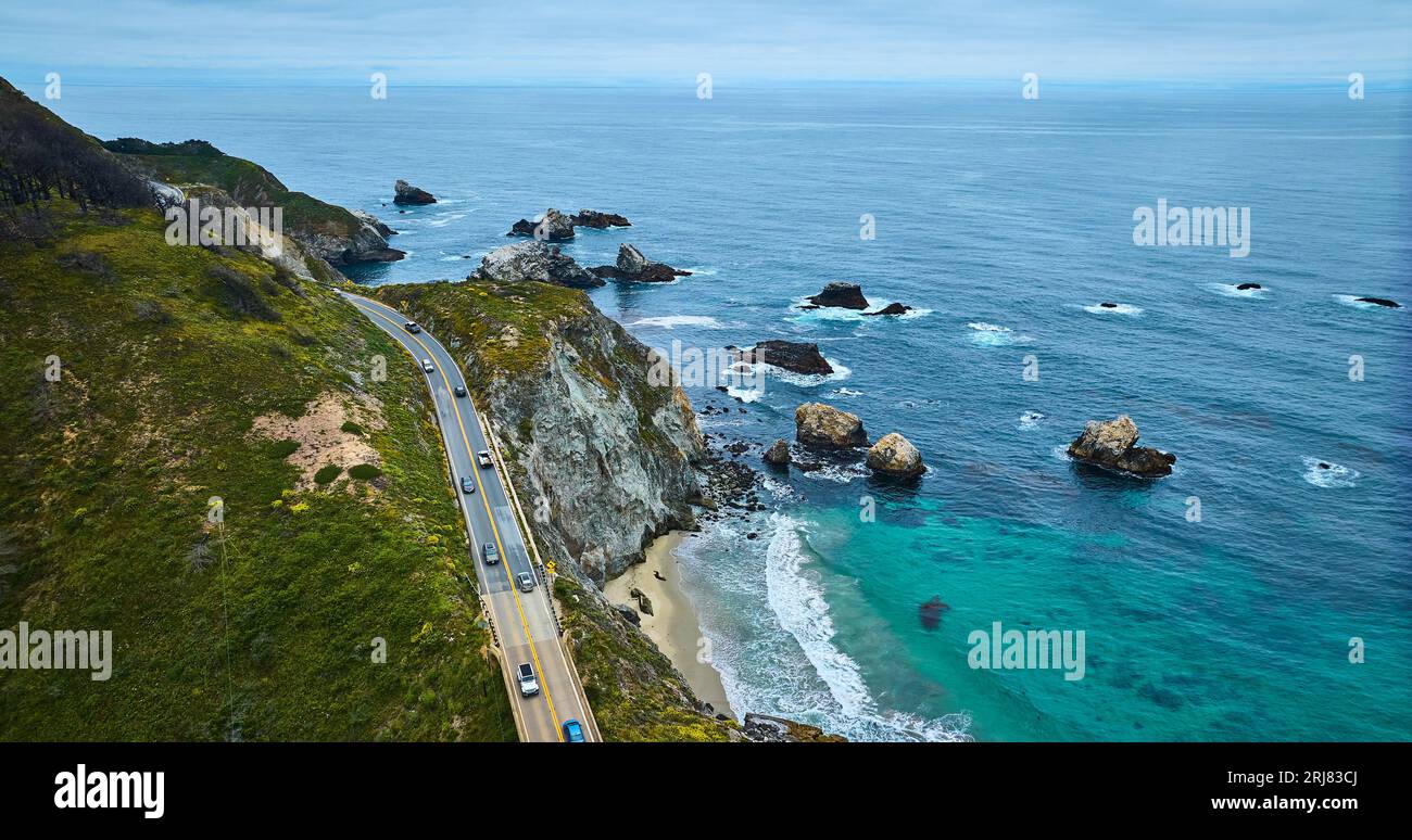 Aereo sopra l'autostrada accanto alle onde azzurre dell'oceano che si infrangono contro rocce e spiagge sabbiose Foto Stock