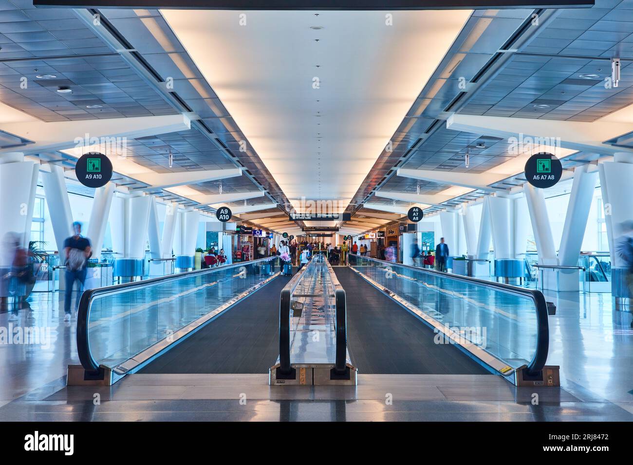 Due passaggi pedonali in movimento fianco a fianco con persone che camminano all'estremità dell'aeroporto Foto Stock