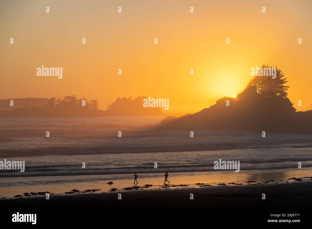 Sagome di persone che corrono su Cox Bay Beach al tramonto, Vancouver Island, British Columbia, Canada. Foto Stock