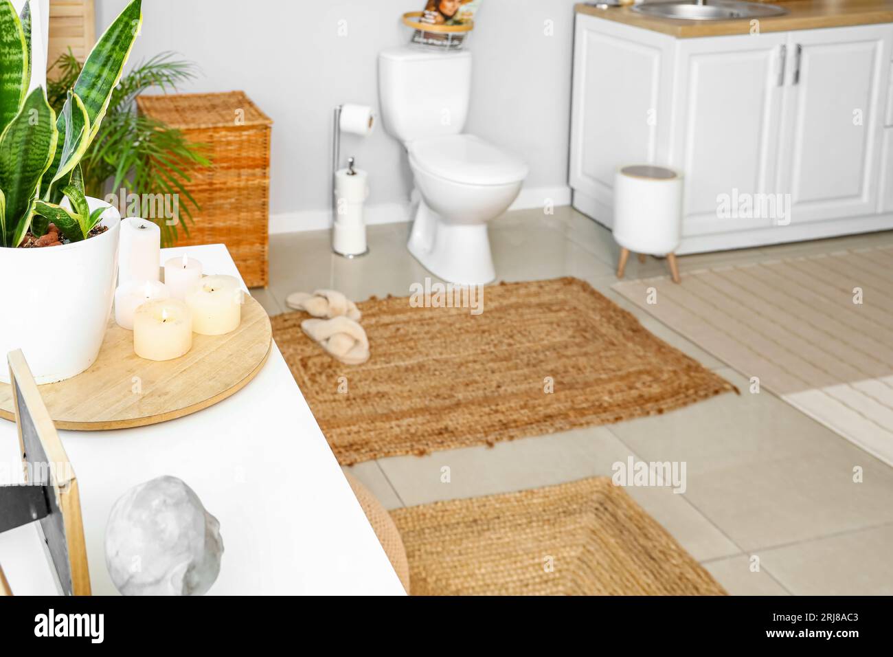 Interno della stanza da bagno con luce, WC in ceramica e candele accese Foto Stock