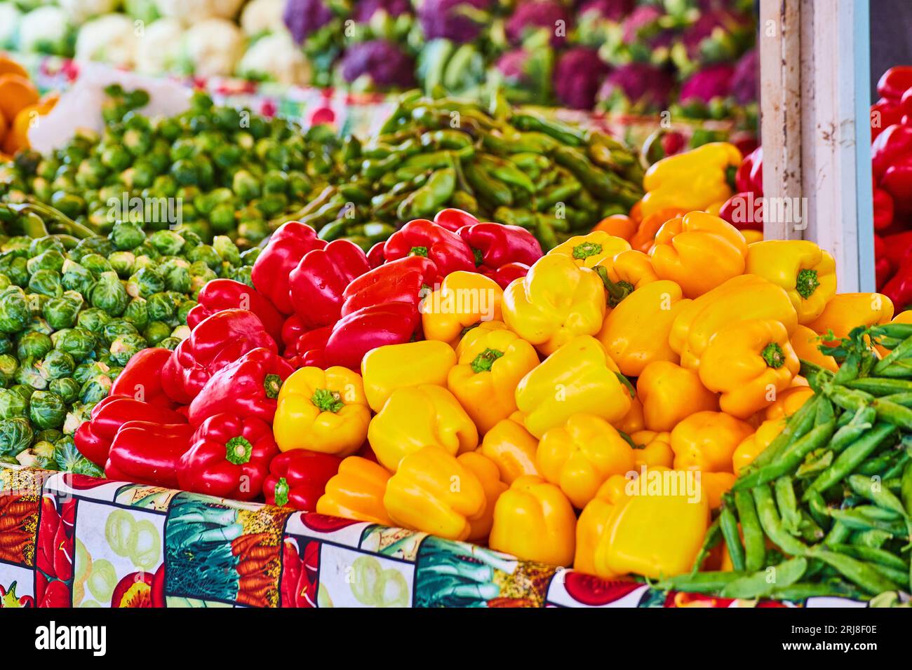 Peperoni rossi e gialli e varietà di altre verdure sui tavoli Foto Stock