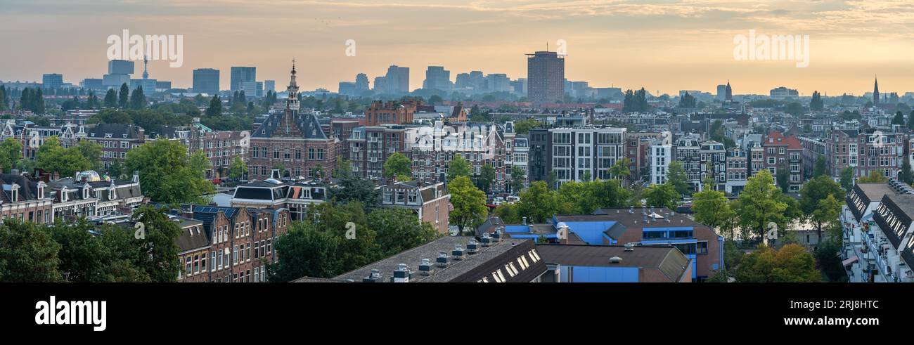 Panorama di Amsterdam, vista delle tradizionali case sul canale lungo il fiume Amstel e dei moderni ed alti edifici nel quartiere finanziario Zuidas nel Foto Stock