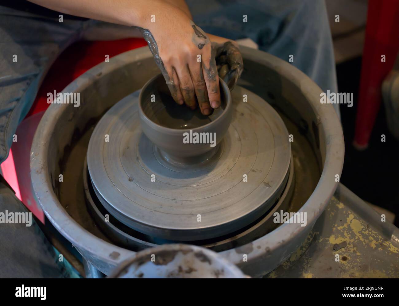 Mani che fanno una tazza di ceramica sulla ruota di potter . Aula di officina concettuale Foto Stock