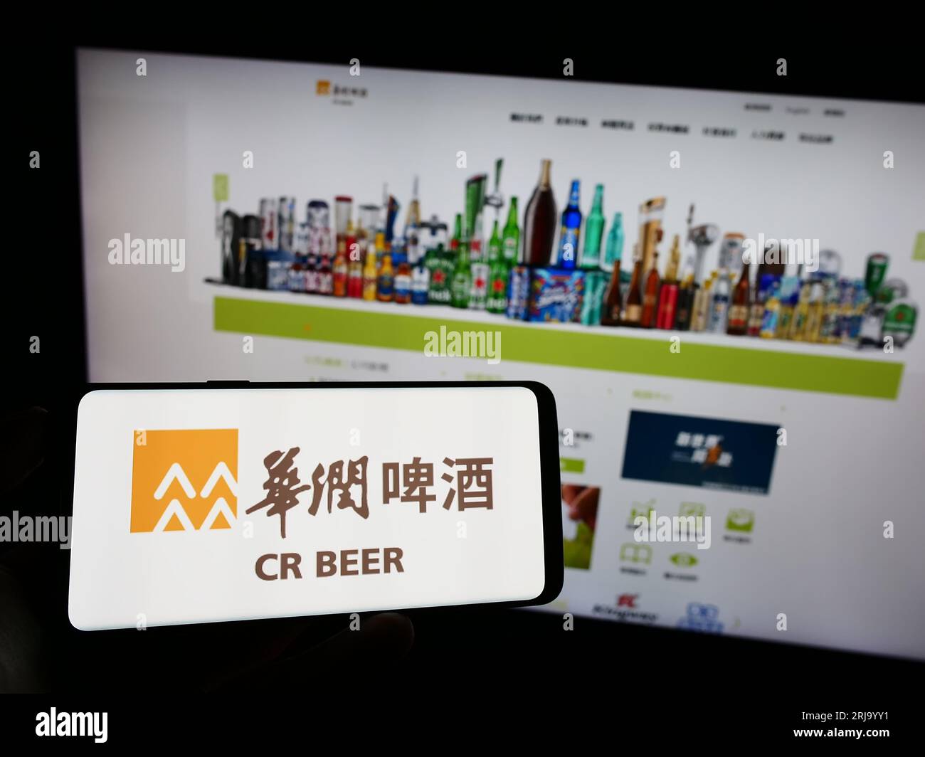 Persona che possiede un telefono cellulare con il logo dell'azienda China Resources Beer Holdings Co. Ltd. Sullo schermo davanti alla pagina Web. Concentrarsi sul display del telefono. Foto Stock