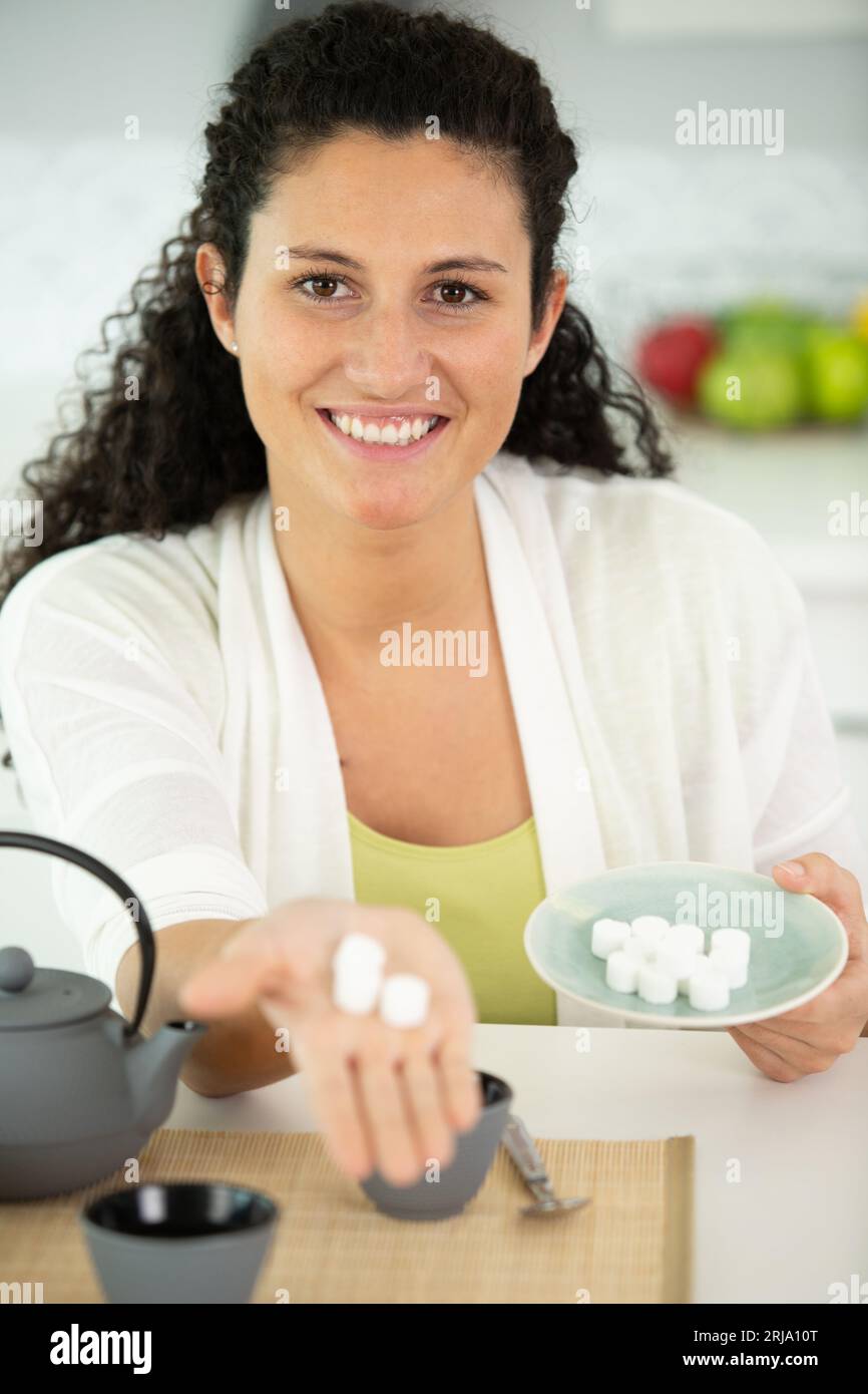 donna felice che tiene la cubetta di zucchero in mano Foto Stock