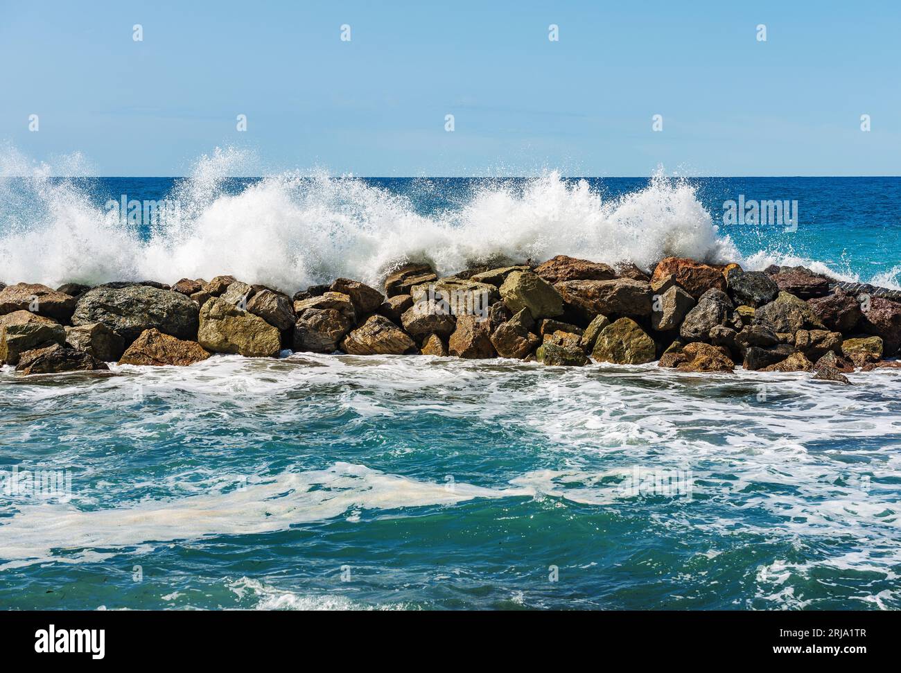Grandi onde bianche del mare si infrangono sulle rocce. Breakwater vicino al piccolo villaggio di Framura. La Spezia, Liguria, Italia, Europa. Mar Mediterraneo. Foto Stock