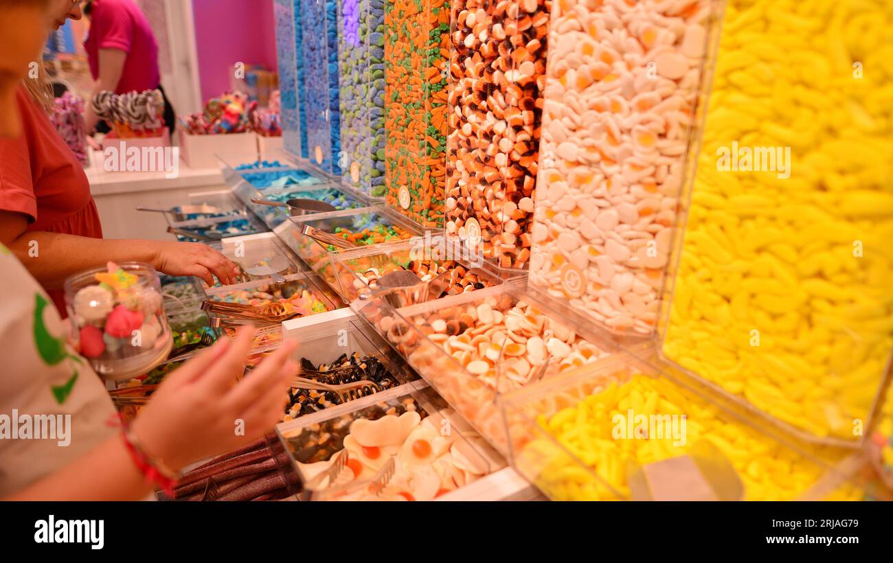 Vasi di plastica pieni di caramelle colorate in negozio. Foto Stock